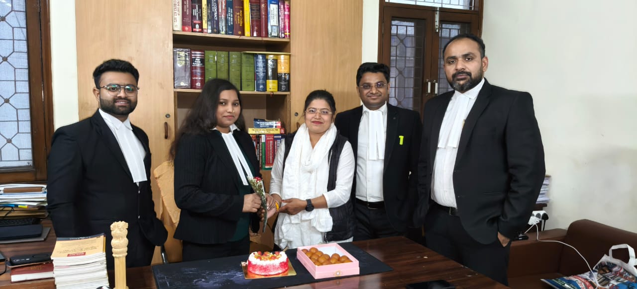 A professional celebration among legal colleagues, sharing sweets and a cake in an office setting to mark a special milestone.a professional's multifaceted journey, showcasing her role in the legal field alongside significant community leadership